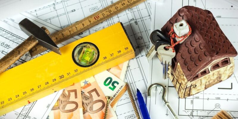 Säästa raha planeerimisega, ehitusjoonis, kollane joonlaud, lood, haamer, euro rahatähed ja majamakett koos võtmetega