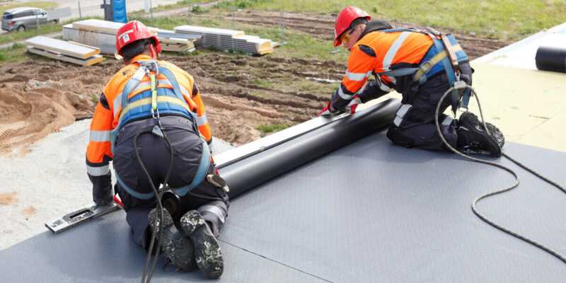 Katusefirma Evari Ehitus meistrid rullmaterjalist lamekatuse kattekihi paigaldamisel turvavarustusega