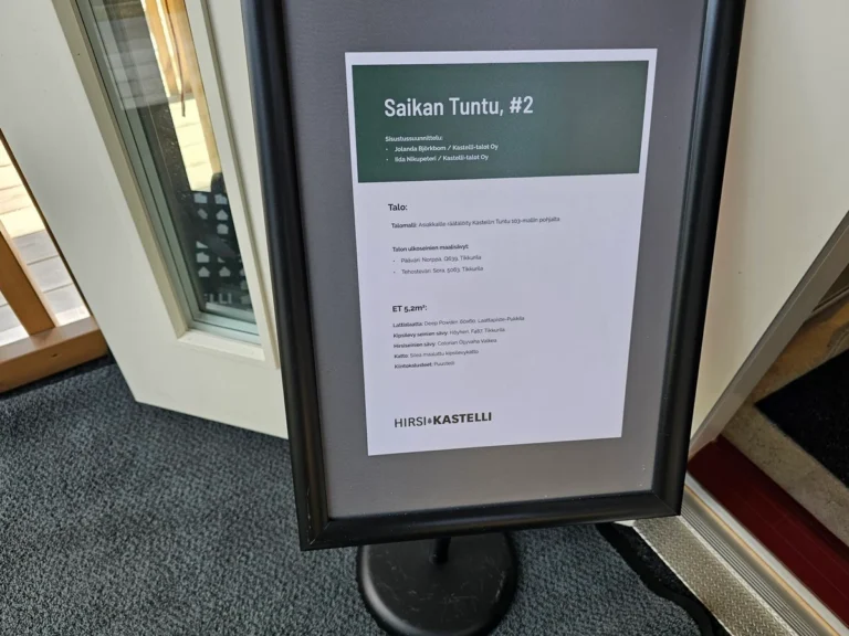 NÄIDISMAJA INFOTAHVEL ELAMUMESSIL: HIRSI-KASTELLI ERAMU SAIKAN TUNTU DETAILNE TOOTE- JA MATERJALIINFO LEMPÄÄLÄS. Soome Elamumess 2026 Lempääläs – Hirsi-Kastelli näidiselamu Saikan Tuntu infotahvel